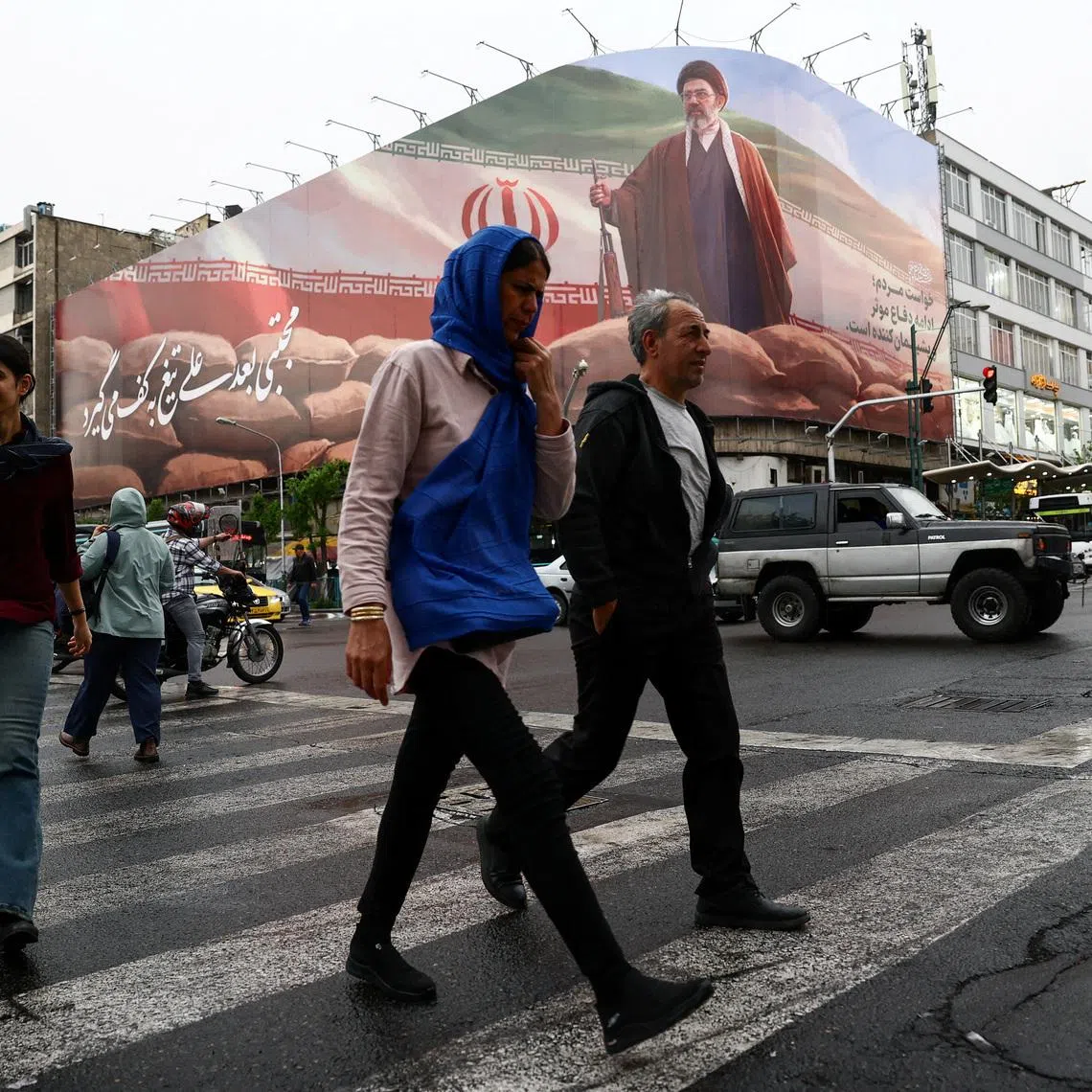 People walk near a billboard featuring an image of Iran's new Supreme Leader, Mojtaba Khamenei, amid a ceasefire between the U.S. and Iran, in Tehran, Iran, April 20, 2026. Majid Asgaripour/WANA (West Asia News Agency) via REUTERS