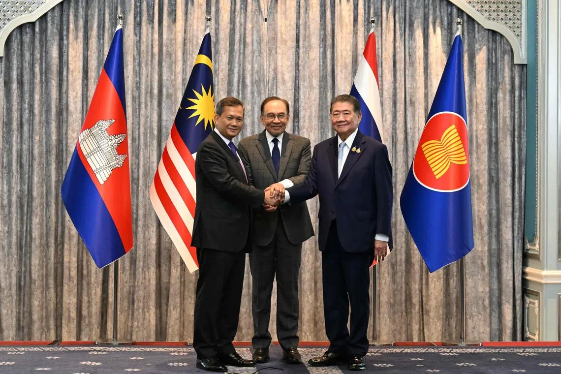 Malaysia's Prime Minister Anwar Ibrahim (C), Cambodia's Prime Minister Hun Manet (L) and Thailand's acting Prime Minister Phumtham Wechayachai (R) pose for photos as they shake hands following a press conference after talks on a possible ceasefire between Thailand and Cambodia in Putrajaya on July 28, 2025. Thailand and Cambodia began discussing a ceasefire in their festering border dispute on July 28, as the deadly skirmish dragged into a fifth day. (Photo by MOHD RASFAN / POOL / AFP)