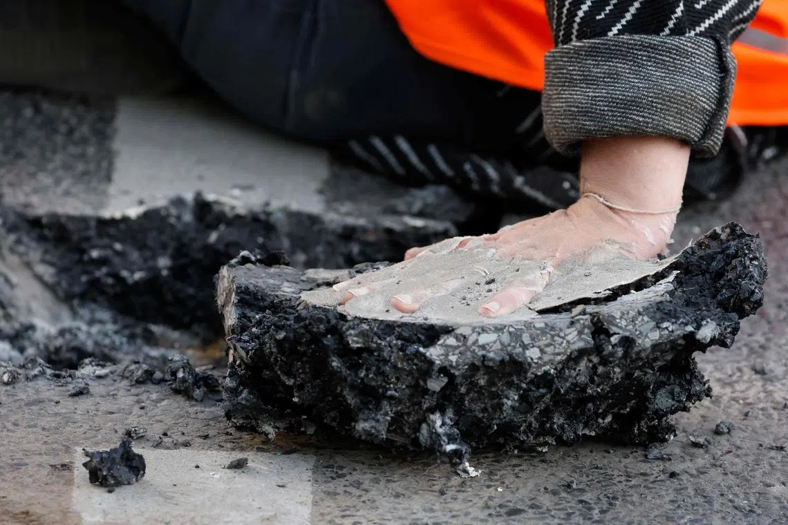 A climate activist who glued herself to the street in order to draw attention to the climate emergency carrying a piece of road surface on her hand on Sept 18 in Berlin, Germany.