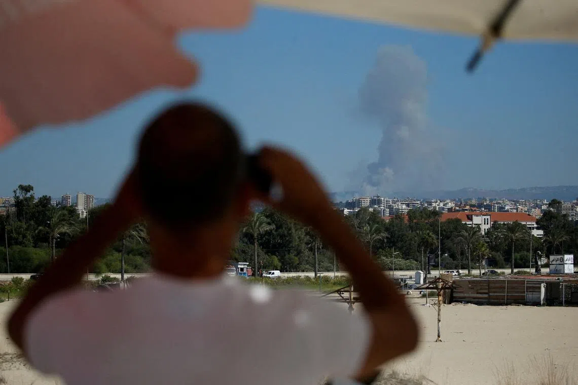 FILE PHOTO: A man watches as smoke billows over southern Lebanon following an Israeli strike, amid ongoing cross-border hostilities between Hezbollah and Israeli forces, as seen from Tyre, Lebanon September 26, 2024. REUTERS/Amr Abdallah Dalsh/File Photo