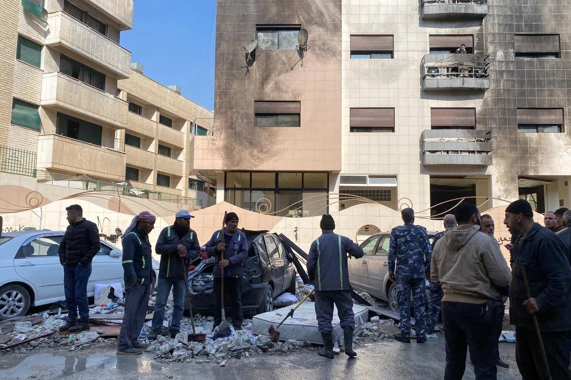 Workers and people stand near a damaged building after, according to Syrian state media reports, several Israeli missiles hit a residential building in the Kafr Sousa district, Damascus, Syria  February 21, 2024. REUTERS/Firas Makdesi
