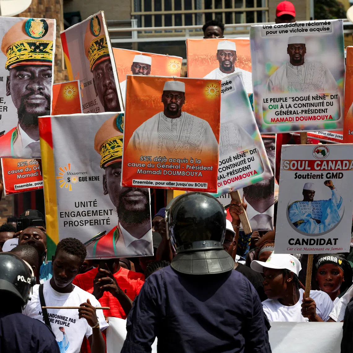 FILE PHOTO: Police officers stand guard in front of supporters of Guinean leader Mamadi Doumbouya who hold campaign signs, as they wait for him to submit his candidacy at the Supreme Court ahead of the presidential election scheduled for December 28, in Conakry, Guinea November 3, 2025. REUTERS/Luc Gnago/File Photo