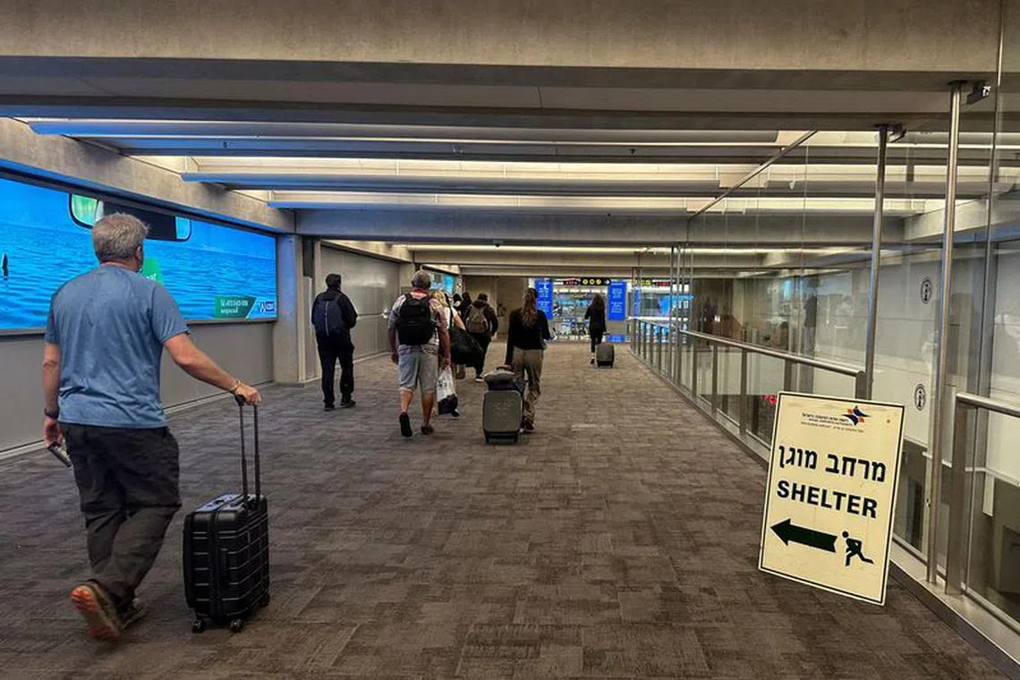 FILE PHOTO: People walk next to a sign directing for Shelter after landing in Israel at the arrivals section of Ben Gurion International airport in Lod near Tel Aviv, Israel  October 11, 2023 REUTERS/Marius Bosch