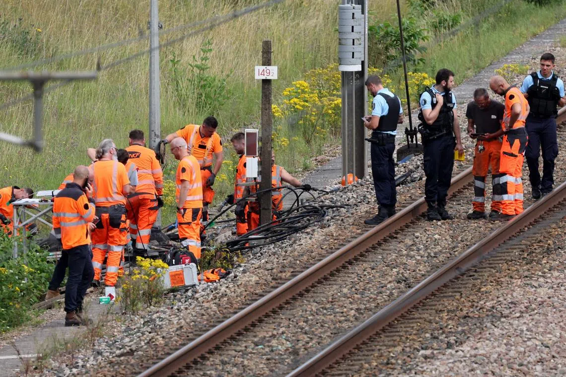 SNCF employees and French gendarmes inspect the scene of a suspected attack on the high speed railway network at Croiselles, northern France ,on July 26, 2024. 