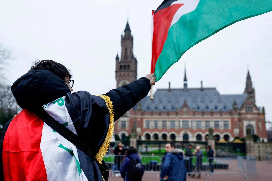 FILE PHOTO: A man waves a Palestinian flag as people protest on the day of a public hearing held by The International Court of Justice (ICJ) to allow parties to give their views on the legal consequences of Israel's occupation of Palestinian territories before eventually issuing a non-binding legal opinion, in The Hague, Netherlands, February 21, 2024. REUTERS/Piroschka van de Wouw/File Photo