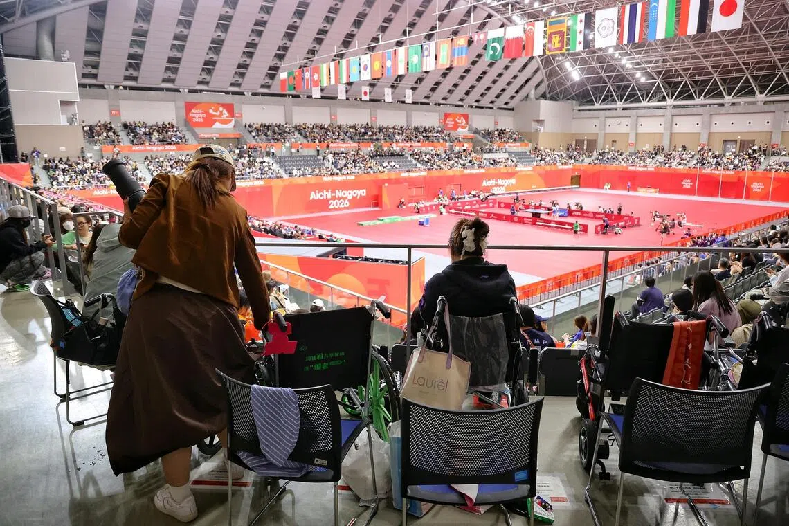 One of the Chinese table tennis fan, equipped with a telephoto lens, standing up from her wheelchair to find another angle for photos.
