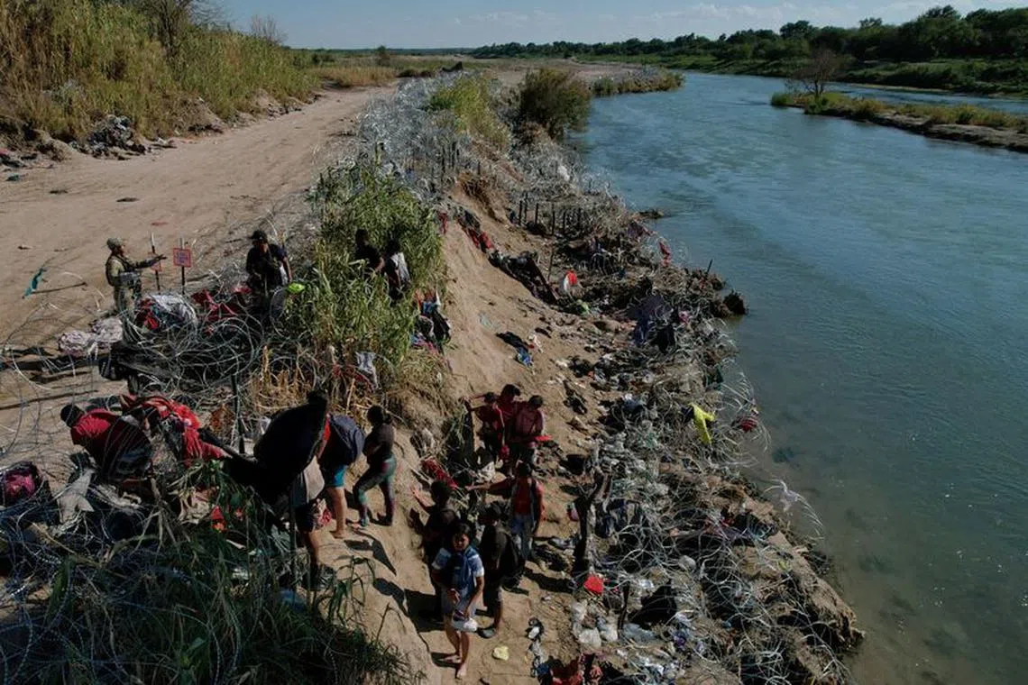 FILE PHOTO: Members of the Texas National Guard try to dissuade migrants from climbing over the razor wire after they crossed the Rio Grande in Eagle Pass, Texas, U.S., September 29, 2023.   REUTERS/Brian Snyder/File Photo