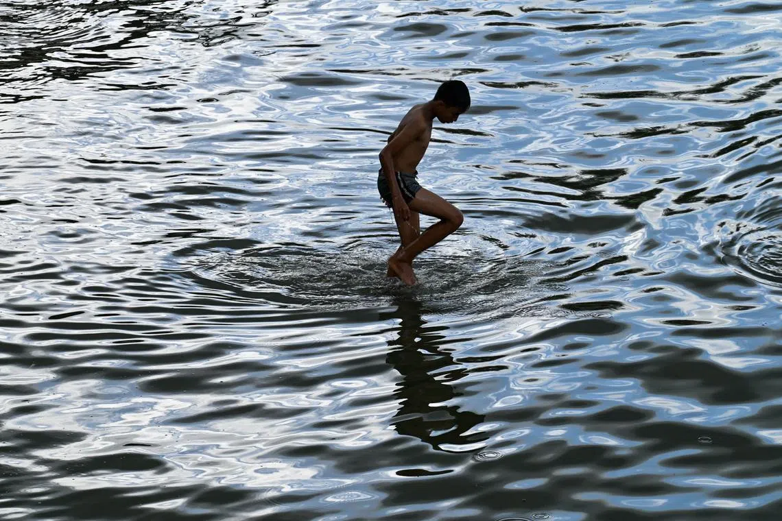 A boy stands in shallow water by a beach in Banda Aceh on December 15, 2022. 
