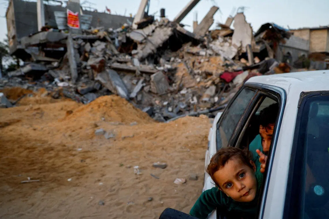 A Palestinian child looking out of a vehicle window near a house destroyed by Israeli air strikes during recent fighting between Israel-Gaza, after a ceasefire between Israel and Palestinian factions was agreed, in the northern Gaza Strip, May 15.