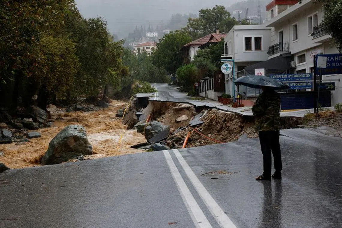A person stands on a road which collapsed due to the impact of storm Daniel, near a nursing home in the city of Volos, Greece, September 6, 2023. REUTERS/Louisa Gouliamaki