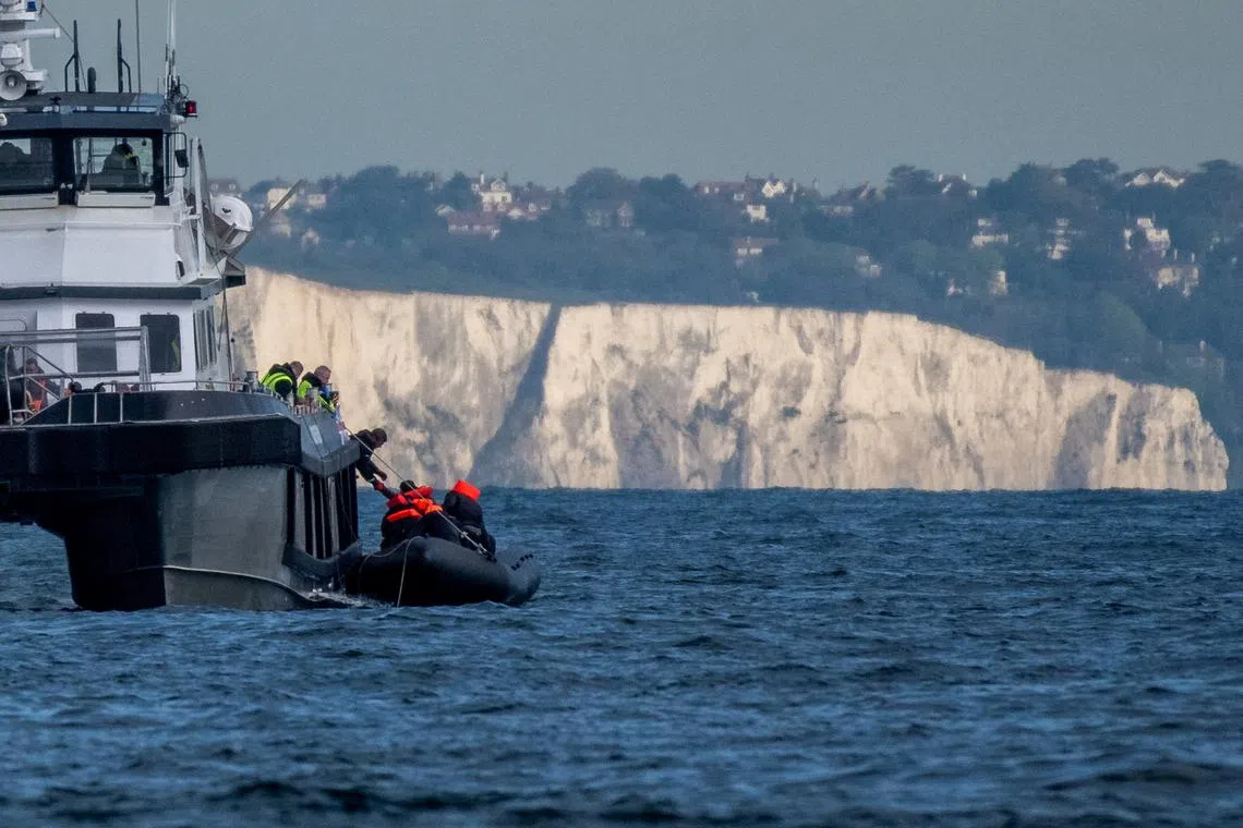 FILE PHOTO: A British Border Force vessel picks up an inflatable dinghy carrying migrants in front of the white cliffs of Dover in the English Channel, Britain, May 4, 2024. REUTERS/Chris J. Ratcliffe/File Photo
