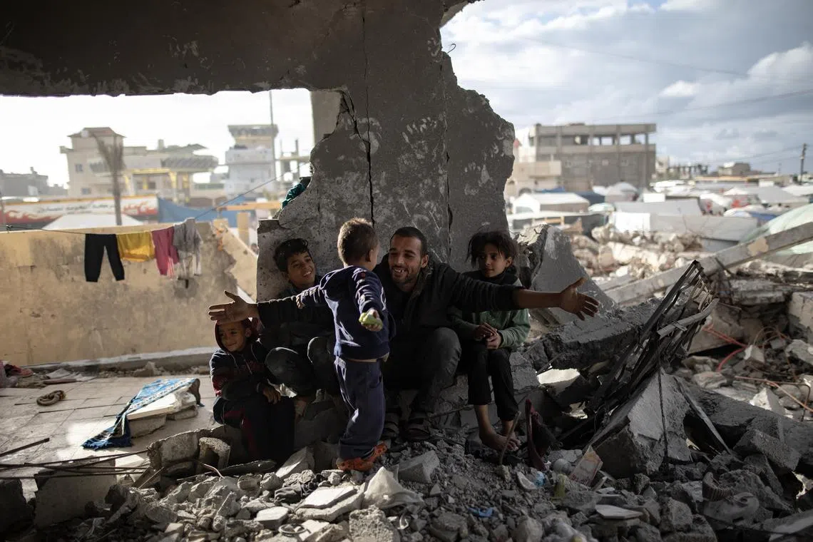 Displaced Palestinian Muhammad Al-Durra, 41, hangs clothes as he speaks to one of his children at the destroyed house they have taken shelter in, in the city of Rafah, in southern Gaza.