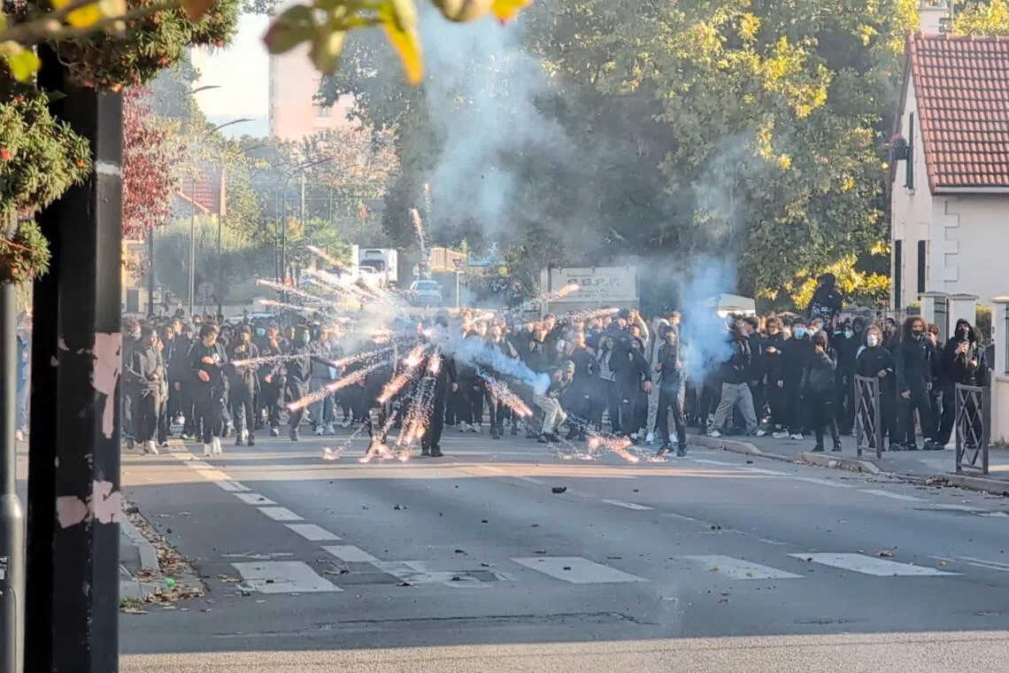 A protester launches a firework during clashes with the police in the streets near Paris on Oct 5.