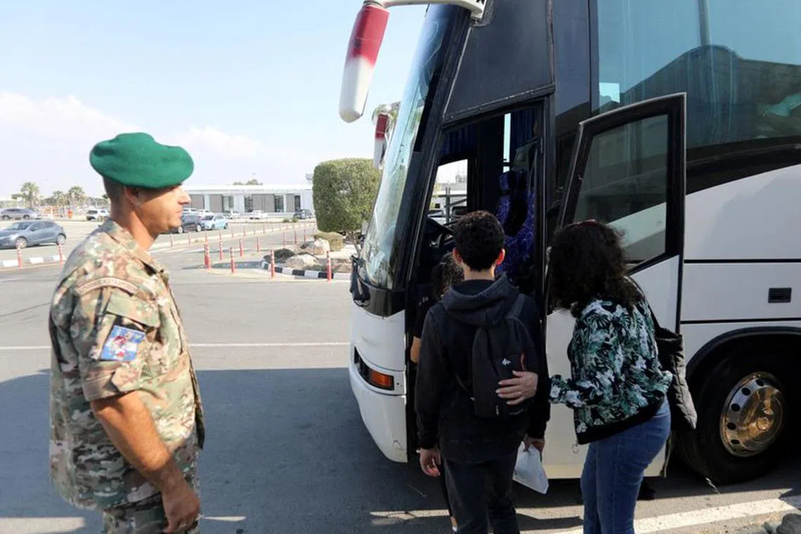 FILE PHOTO: People who were evacuated from Israel, board a bus after arriving at the Larnaca International Airport, in Larnaca, Cyprus, October 11, 2023. REUTERS/Yiannis Kourtoglou/File Photo