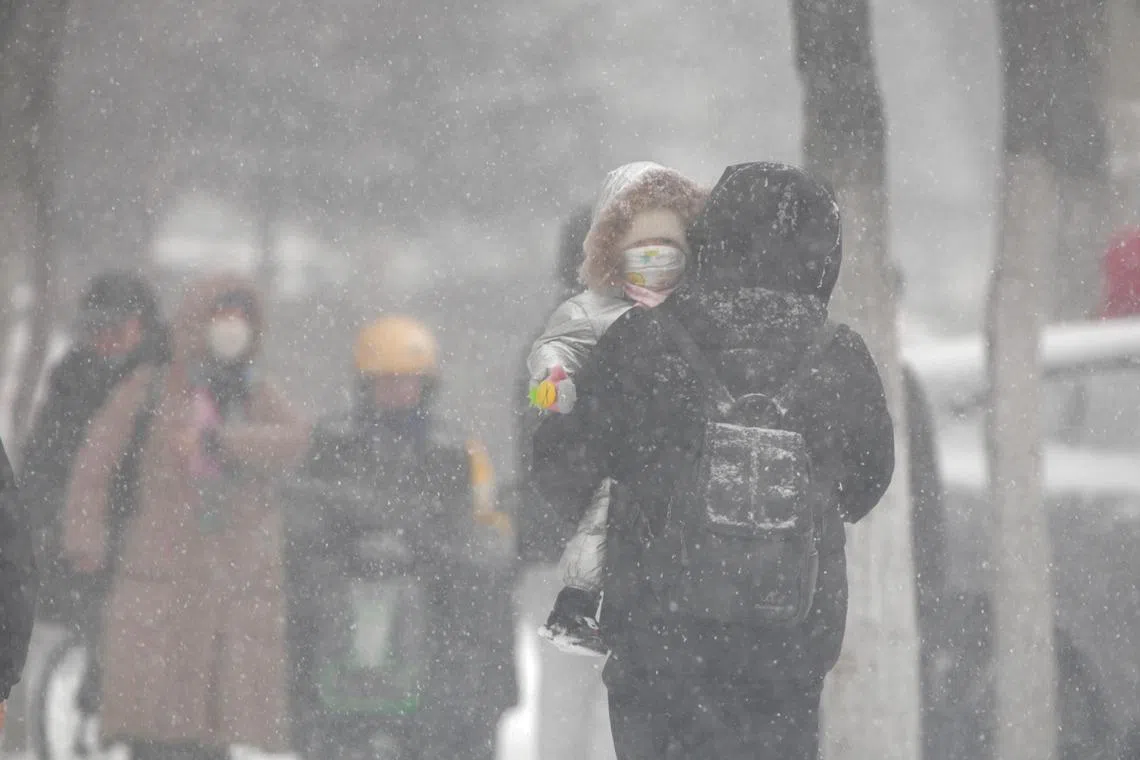 epa11740025 A pedestrian carries a child on a snowy day in Qiqihar, northeast China's Heilongjiang Province, 25 November 2024. China's meteorological authority issued a yellow alert for snowstorms on 25 November, with blizzards expected to hit parts of the country's northeast.  EPA-EFE/XINHUA / WANG YONGGANG CHINA OUT / UK AND IRELAND OUT  /       MANDATORY CREDIT EDITORIAL USE ONLY