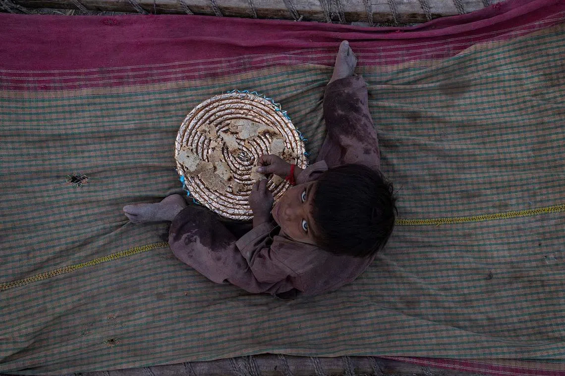 Muhammad Rahan, 3, eating a chapati outside his shelter during a heatwave along the banks of the Upper Chenab Canal in Sialkot, Pakistan, June 11, 2025. 