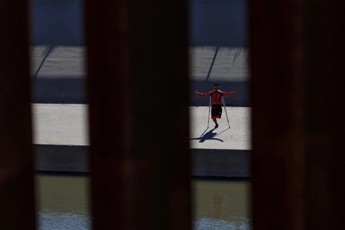 A migrant seeking asylum in the U.S. reacts as border patrol agents drive by the border fence at the Rio Bravo river, the border between Mexico and the U.S., as seen from El Paso, Texas, U.S., December 22, 2022. 