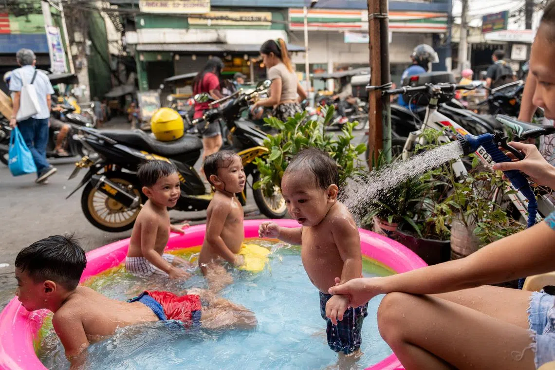 Children play in an inflatable pool beside a street, amid the hot weather during summer, in Manila, Philippines, April 26, 2023. 