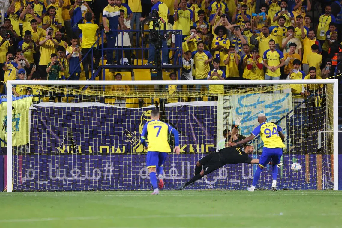 Al-Nassr's Brazilian forward Talisca scoring a penalty as Ronaldo races in for the rebound  in the Saudi Pro League match against Abha in Riyadh on March 18, 2023.