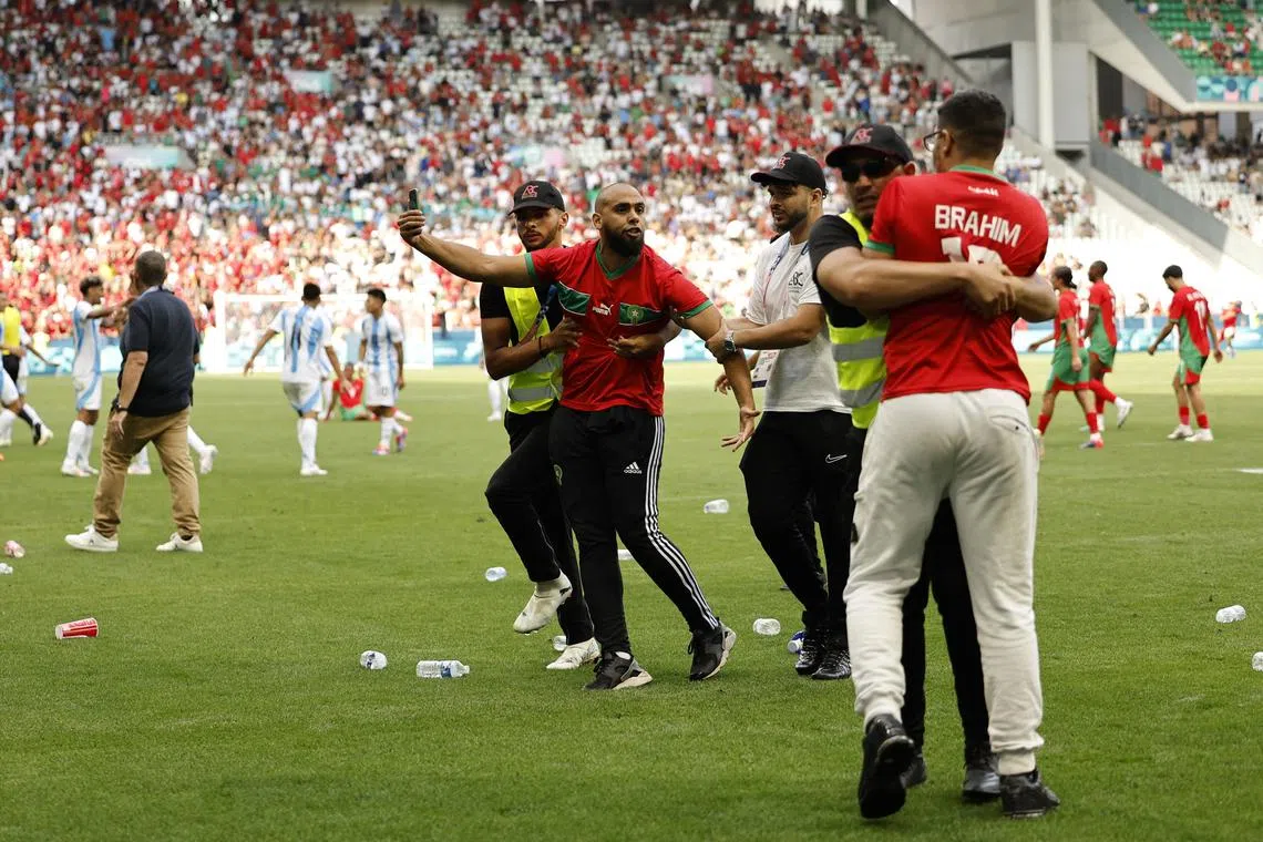 Paris 2024 Olympics - Football - Men's Group B - Argentina vs Morocco - Geoffroy-Guichard Stadium, Saint-Etienne, France - July 24, 2024. Pitch invaders are detained by stewards after the match. REUTERS/Thaier Al-Sudani