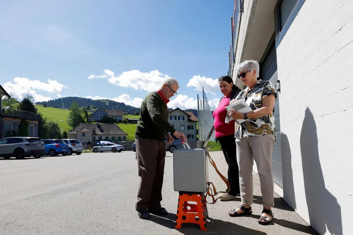 People vote in front of the school on a plan backed by the right-wing Swiss People's Party (SVP) to limit population growth to 10 million inhabitants, in Hundwil, Switzerland, June 14, 2026.  REUTERS/Michaela Stache