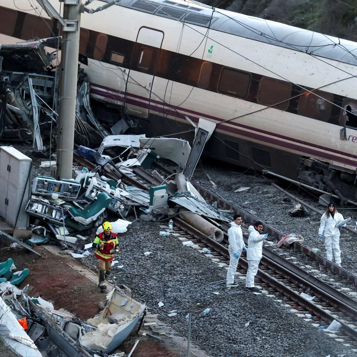 A firefighter and members of the Spanish Civil Guard work next to one of the trains involved in the accident, at the site of a deadly derailment of two high-speed trains near Adamuz, in Cordoba, Spain, January 19, 2026. REUTERS/Susana Vera