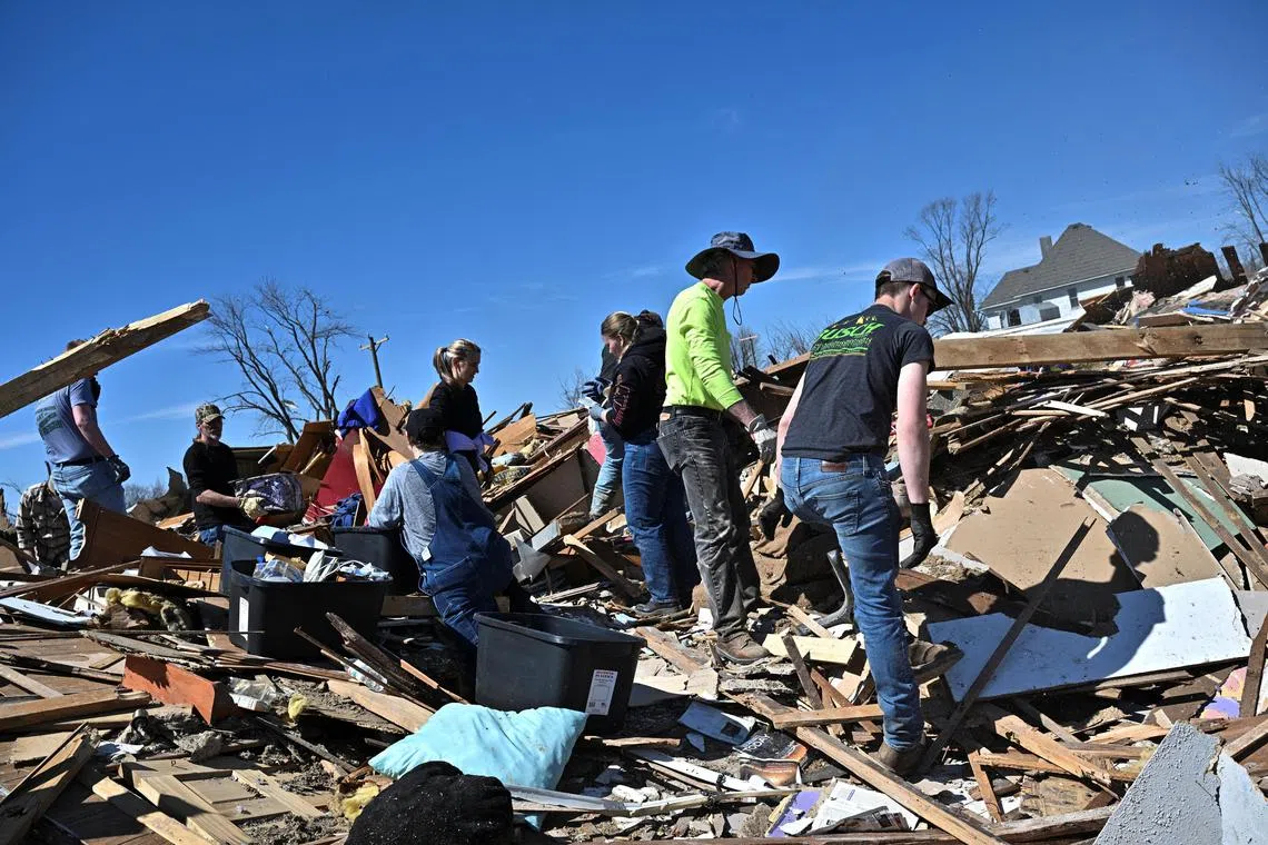Community members and volunteers sort through the debris of a destroyed home, two days after a tornado hit Sullivan, Indiana.