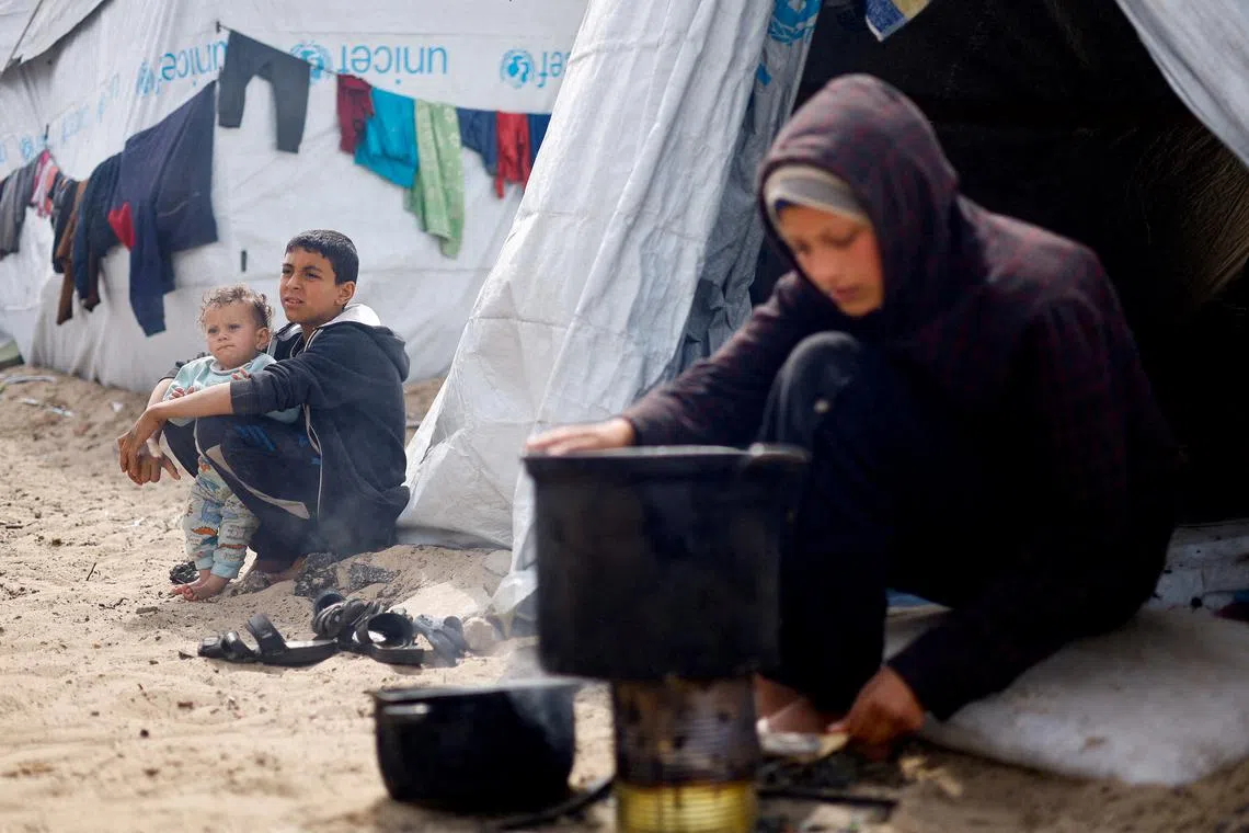 FILE PHOTO: Displaced Palestinian children, who fled their houses due to Israeli strikes, sit at a tent camp, amid the ongoing conflict between Israel and the Palestinian Islamist group Hamas, in Rafah in the southern Gaza Strip, March 6, 2024. REUTERS/Mohammed Salem/File Photo
