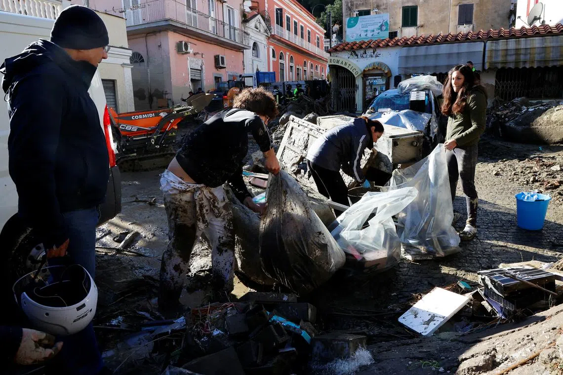 People clear up debris following a landslide on the Italian holiday island of Ischia, Italy, Nov 27, 2022.