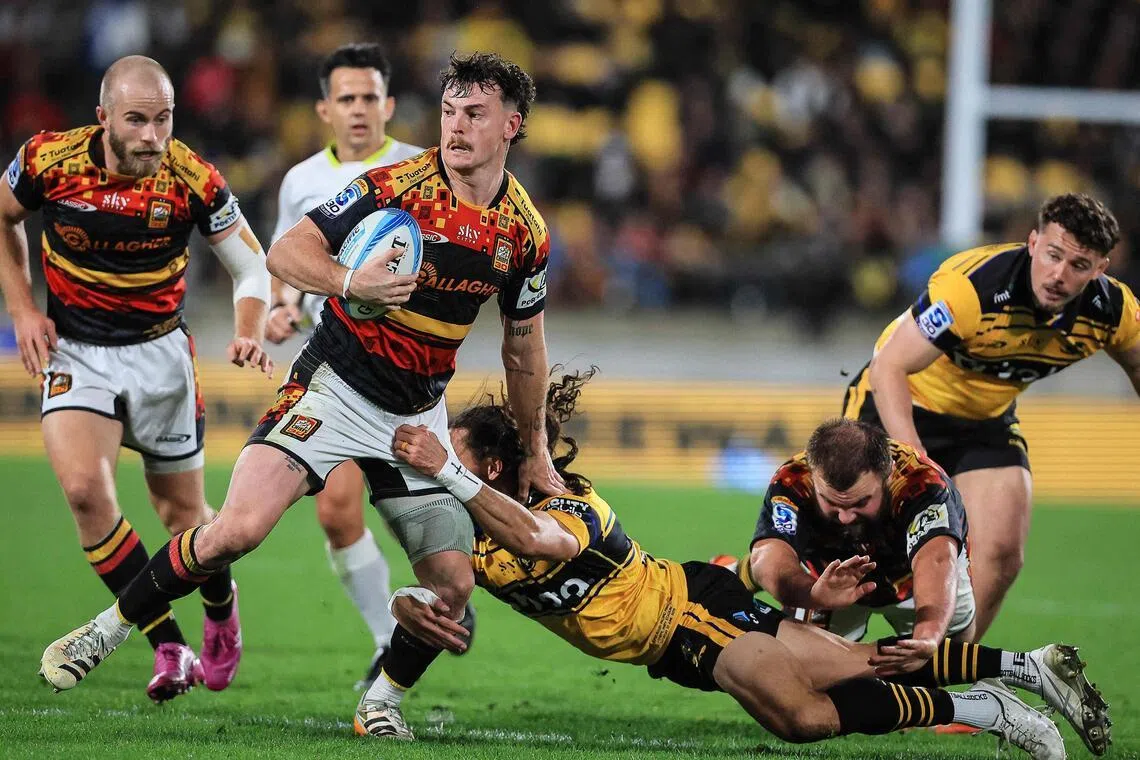 TOPSHOT - Chiefs Leroy Carter breaks the tackle of Hurricanes Ereatara Enari during the Super Rugby Pacific final match between the Wellington Hurricanes and Waikato Chiefs in Wellington on June 20, 2026. (Photo by Grant Down / AFP)
