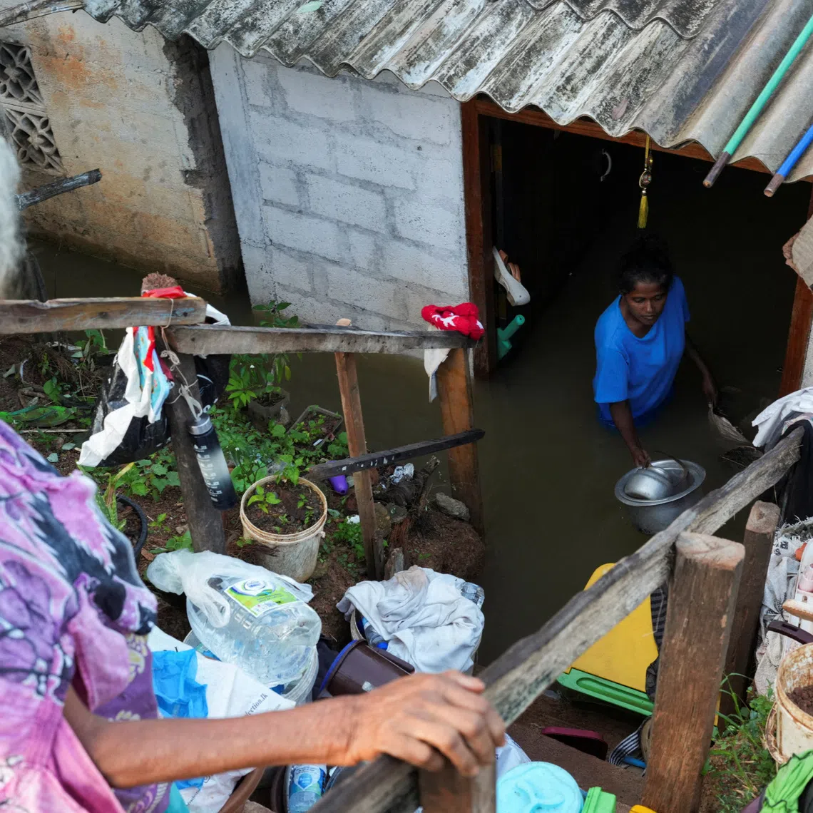 People salvage their belongings from a flooded house along the banks of Kelani River, following Cyclone Ditwah in Peliyagoda, Sri Lanka.