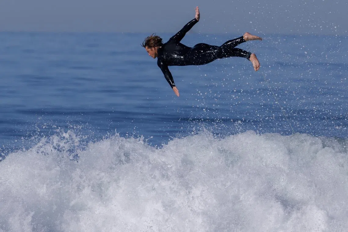 A surfer leaping off his surfboard while surfing at Cardiff State Beach in Encinitas, California, U.S., Nov 27, 2023.  