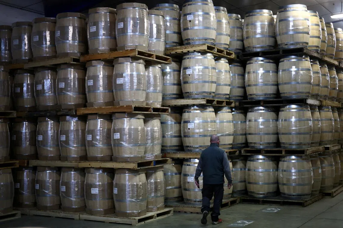 FILE PHOTO: An employee walks past oak barrels at the Tonnelleries Vicard cooperage in Cognac, France, April 3, 2025. REUTERS/Stephane Mahe/File Photo