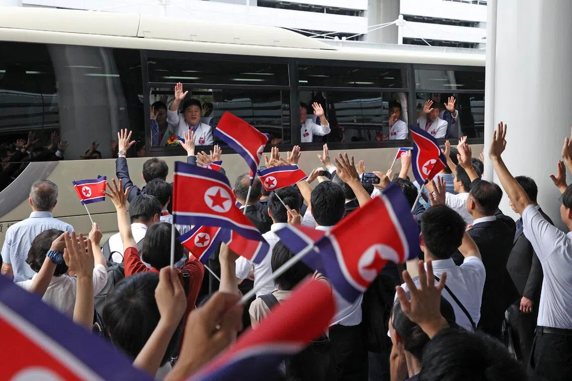 Members of the North Korean men’s football team wave from a bus after arriving at Kansai International Airport on Sept 11.