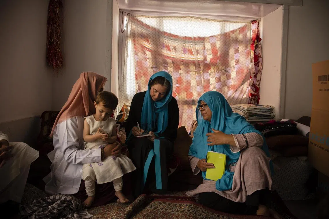 Unicef staff members interview a woman about her health and her child's health at a mobile clinic in the village of Alisha, in Wardak Province, Afghanistan. Since the Taliban administration banned women from aid work, many groups have suspended their operations in the country and warned of permanently shutting down if the ban remains.  