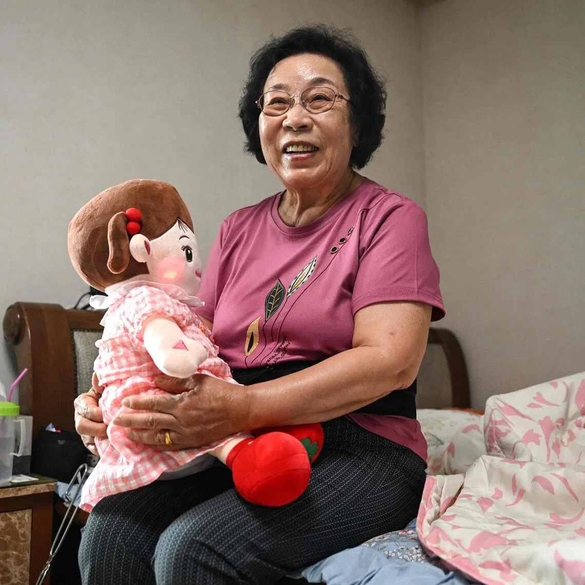 Bang Chun-ja, a 78-year-old South Korean woman who lives alone, holding Hyodol, an AI-powered healthcare doll designed for elderly people, during an interview with AFP at her home in Yongin. 