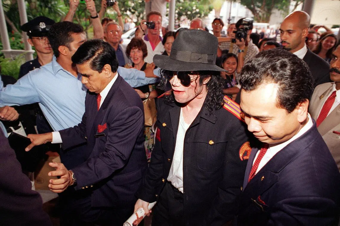 Michael Jackson surrounded by fans and photographers on his arrival at Raffles Hotel in October 1996 for his world tour to promote his HIStory album.