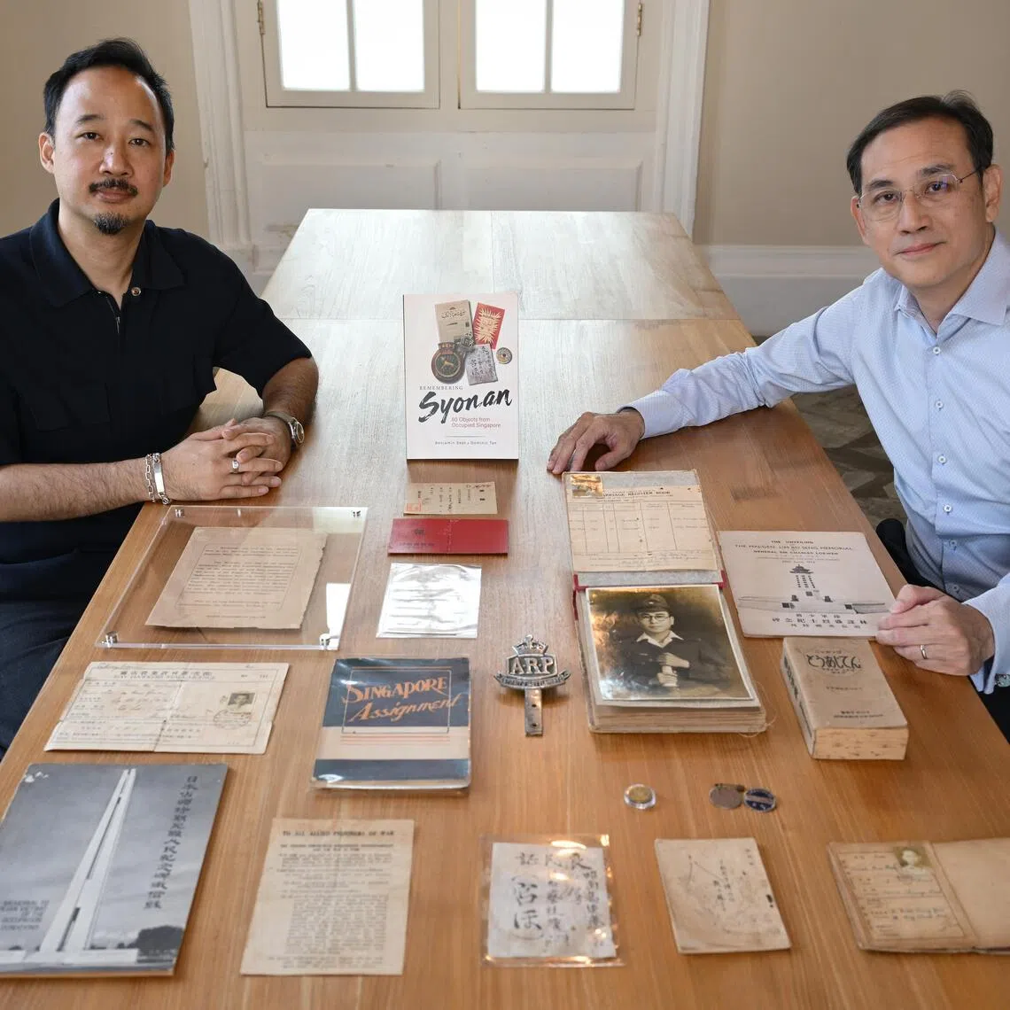 Benjamin Seet (right) and Dominic Tan, co-authors of Remembering Syonan: 80 Objects From Occupied Singapore, with some of the items featured in the book.