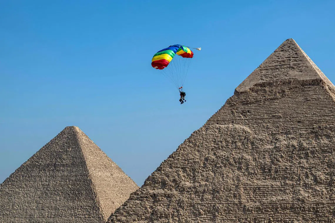 A parachutist descends over the pyramid complex during the 7th edition of the Egypt International Skydiving Festival "Jump Like a Pharaoh", at the Giza plateau near Cairo on Oct 29, 2024.