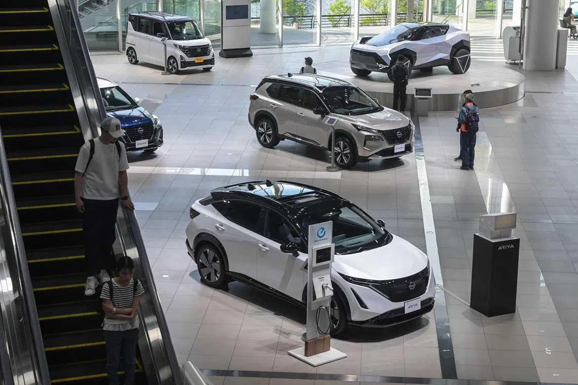 Visitors look at cars on display at the Nissan Gallery inside the headquarters building for Japanese automaker Nissan in the city of Yokohama, Kanagawa prefecture on May 13, 2025. Japanese automaker Nissan posted a huge annual net loss of 4.5 billion USD on May 13, while confirming reports that it planned to cut 20,000 jobs worldwide. (Photo by Richard A. Brooks / AFP)