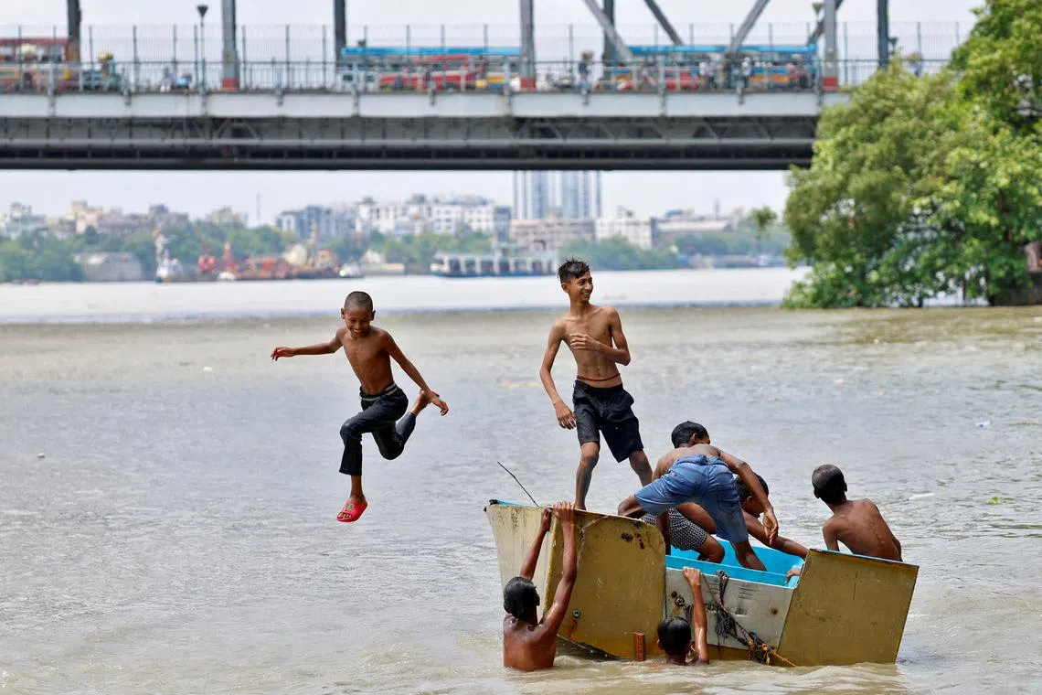 A boy jumps off a boat into the Ganges river to cool off on a hot summer day in Kolkata, India, May 8, 2024. REUTERS/Sahiba Chawdhary/File Photo