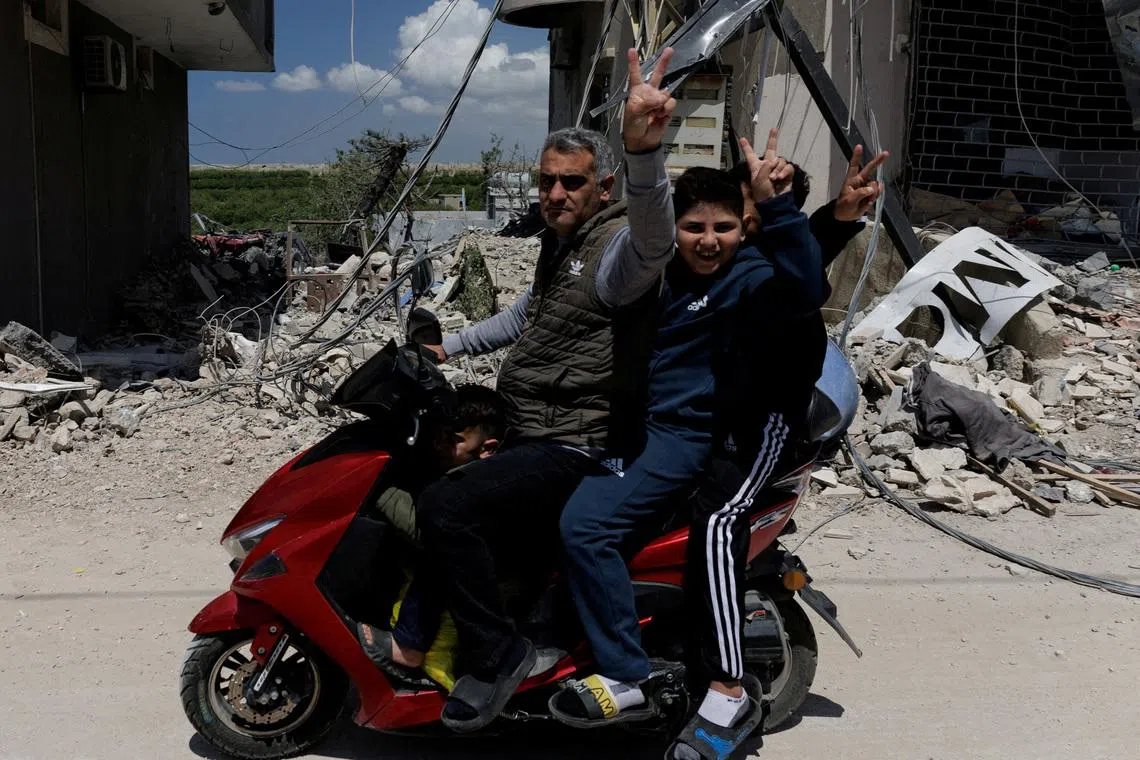 People flash a victory sign as they ride a motorcycle damaged by an Israeli strike, amid a 10-day ceasefire between Lebanon and Israel, in Mansouri village, southern Lebanon, April 21, 2026.