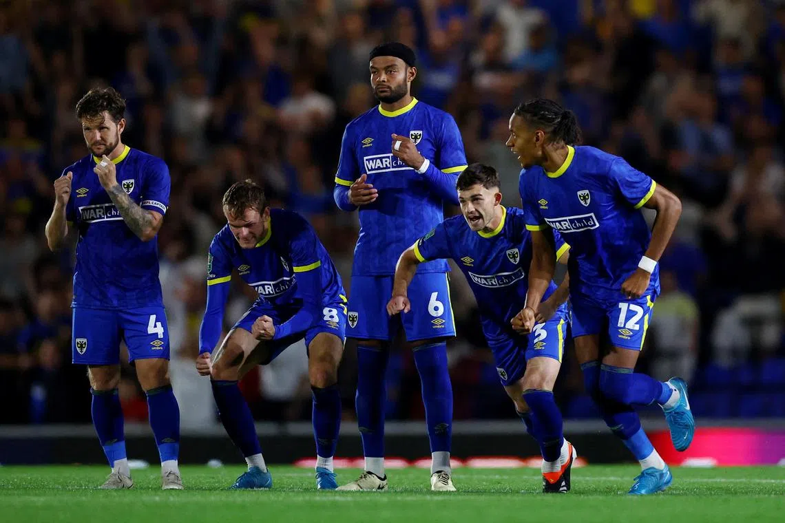 Wimbledon players celebrate winning the penalty shoot-out in their League Cup second-round clash against Ipswich Town.