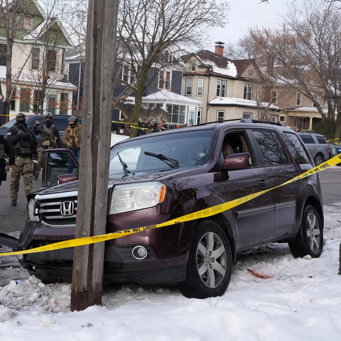 Federal agents gather next to a vehicle with a bullet hole the windshield after the driver was shot in Minneapolis on Jan 7.
