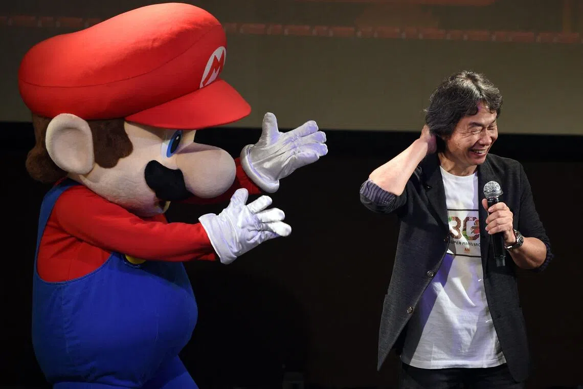 Nintendo game creator Shigeru Miyamoto reacting while standing with character Super Mario on Sept 13, 2015.