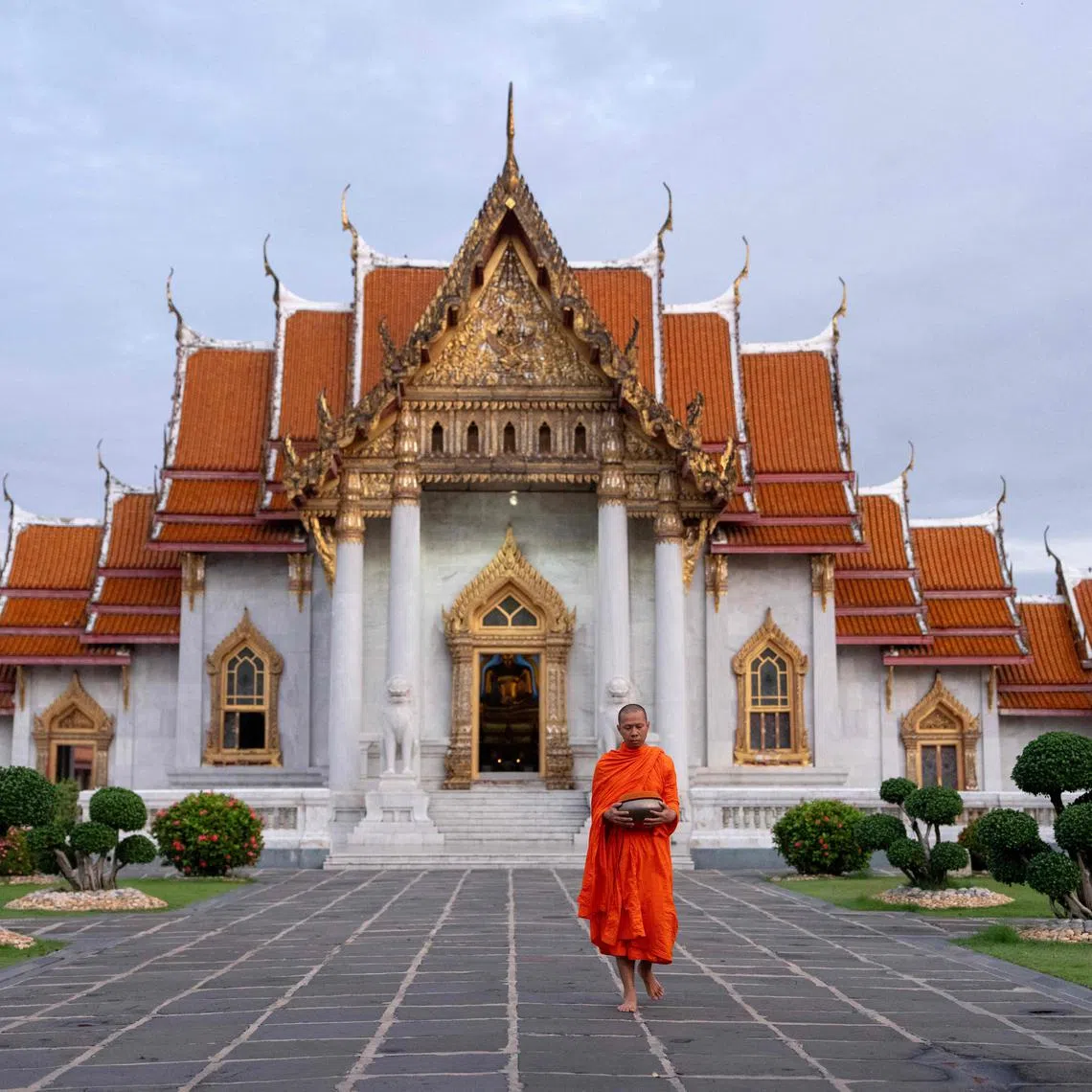 A Buddhist monk prepares to collect alms in front of a temple in Bangkok on July 18, 2025.