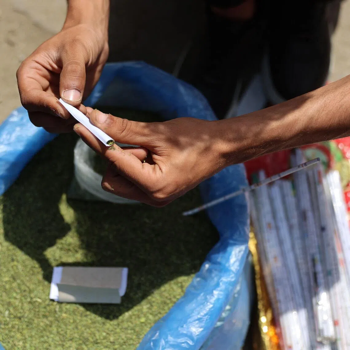 A vendor rolls molokhia leaves, also known as jute mallow, normally used in cooking, into a cigarette at the tobacco market in Gaza City.
