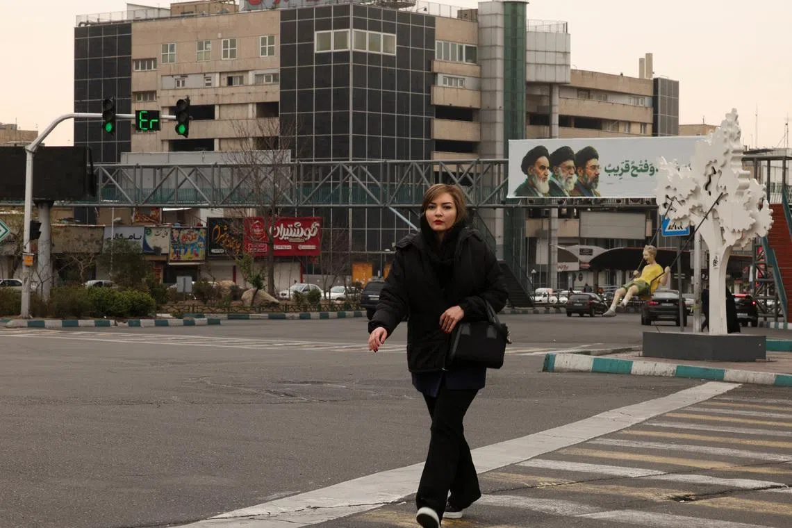 FILE PHOTO: A woman walks across the street, with a banner of all three leaders of Iran, late Ruhollah Khomeini, late Ayatollah Ali Khamenei, and Mojtaba Khamenei in the background, amid the US-Israeli conflict with Iran, in Tehran, Iran, March 15, 2026. REUTERS/Alaa Al-Marjani/File Photo