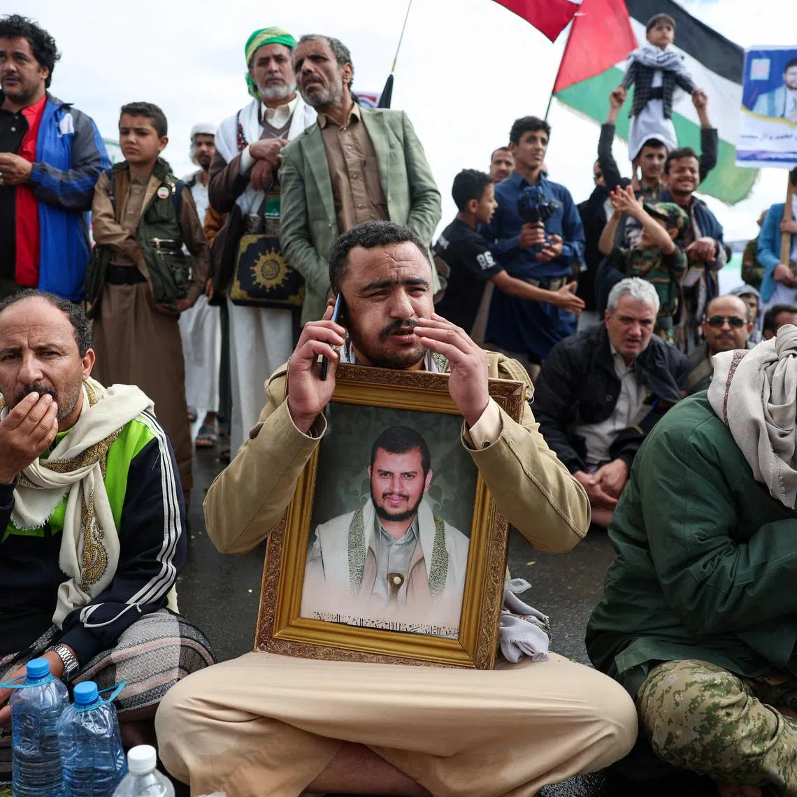 A Houthi supporter holds a poster with an image of the Houthis’s leader, Abdul-Malik al-Houthi, as he speaks on a mobile phone during a demonstration in solidarity with Iran, as the U.S.-Israeli conflict with Iran continues, in Sanaa, Yemen, March 27, 2026. REUTERS/Khaled Abdullah