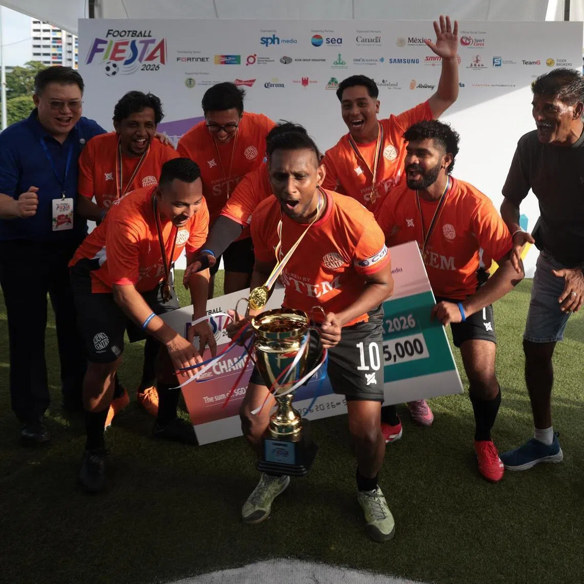 Science Centre’s Mohammed Fazail, 39, lifting the trophy, alongside teammates and SPH CEO Chan Yeng Kit (right) and SEA Limited executive director Bruce Liang (left), after emerging as champions of the Football Fiesta 2026, organised by SPH Media, at the Lion City Sailors Training Centre on 7 June 2026.